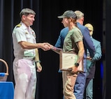 Capt. JD Crinklaw, commander, Puget Sound Naval Shipyard & Intermediate Maintenance Facility, congratulates Maria Gibson, marine pipefitter, Shop 56, Pipefitters, as she receives her apprentice graduation certificate during the 2024 PSNS & IMF Apprentice Program graduation ceremony, Sept. 20, 2024, at Bremerton High School, in Bremerton, Washington. (U.S. Navy photo by Wendy Hallmark)