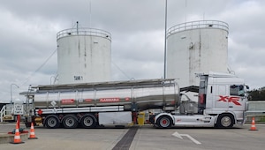 A fuel truck in front of two fuel storage containers