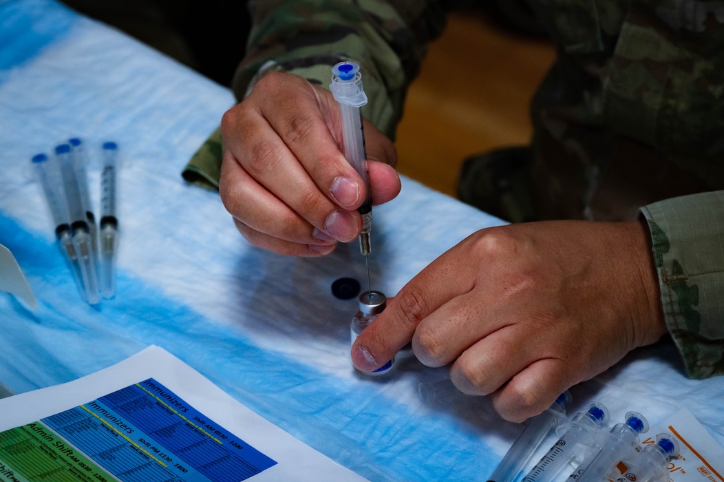 U.S. Air Force Staff Sgt. Mongeriq Barron, 56th Medical Group immunization technician, carefully draws liquid from a small glass vial into a syringe.