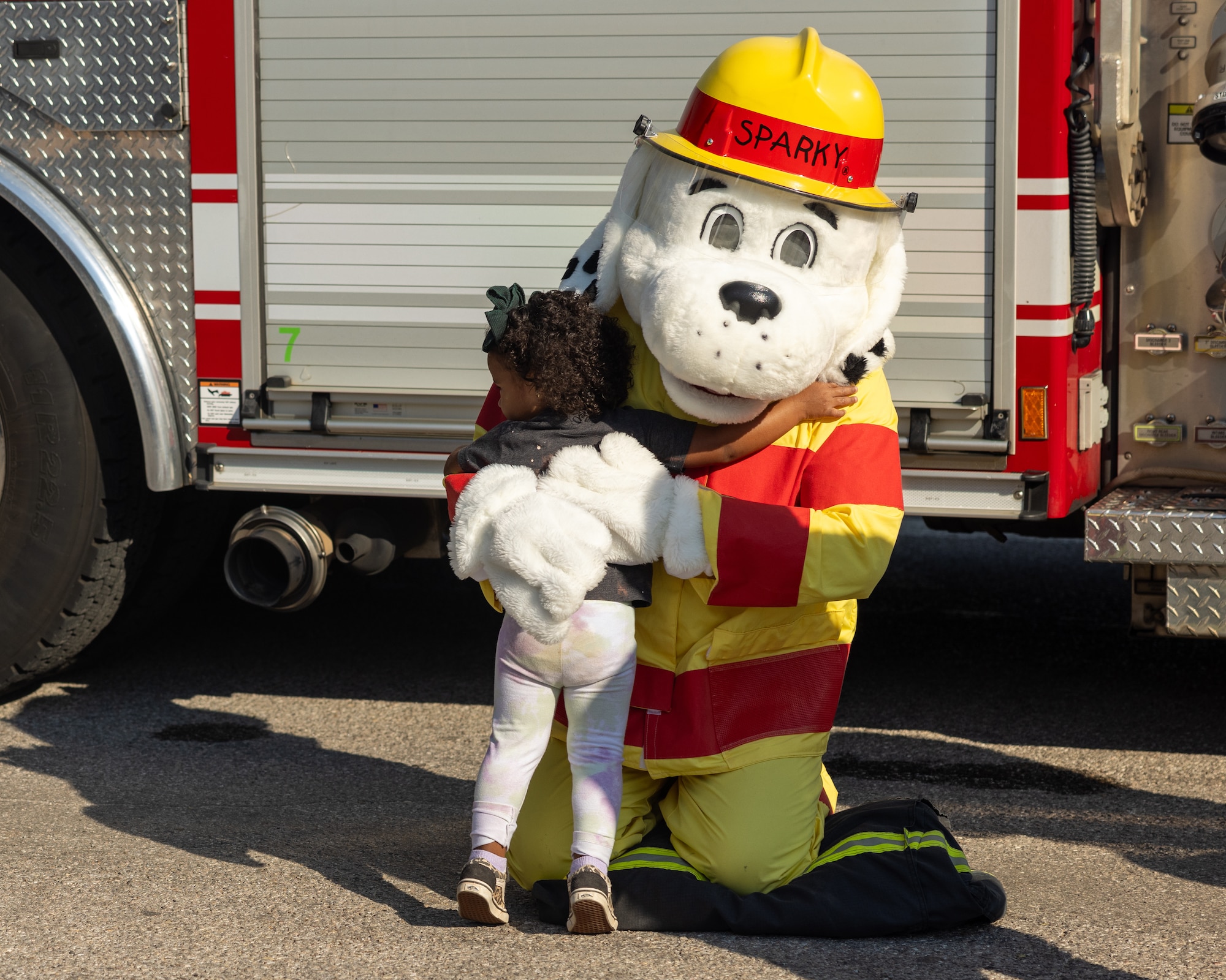 child hugs sparky the fire dog