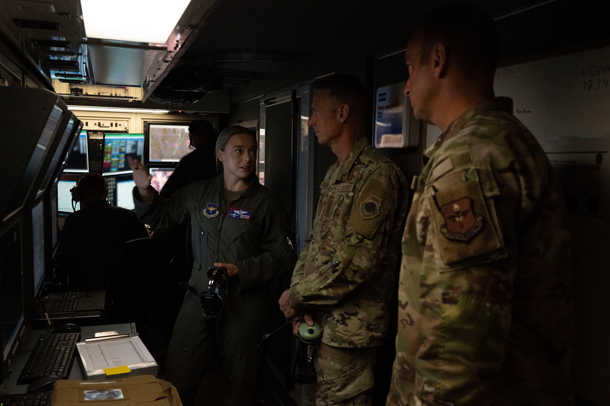 U.S. Air Force Capt. Shannon Sullivan, 9th Attack Squadron chief of weapons and tactics, left, gives a tour of an MQ-9 Reaper ground control station to U.S. Air Force Maj. Gen. Gregory Kreuder, 19th Air Force commander, center, and U.S. Air Force Chief Master Sgt. Keith Scott, 19th Air Force command chief at Holloman Air Force Base, New Mexico, Oct. 8, 2024. Throughout the tour, Kreuder and Scott interacted with Airmen, observed squadron operations, and participated in various hands-on activities. (U.S Air Force photo by Senior Airman Isaiah Pedrazzini)