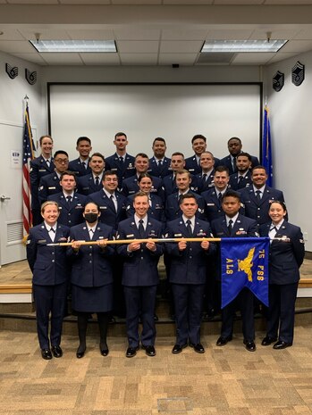 24 Airmen stand in formation in dress blues