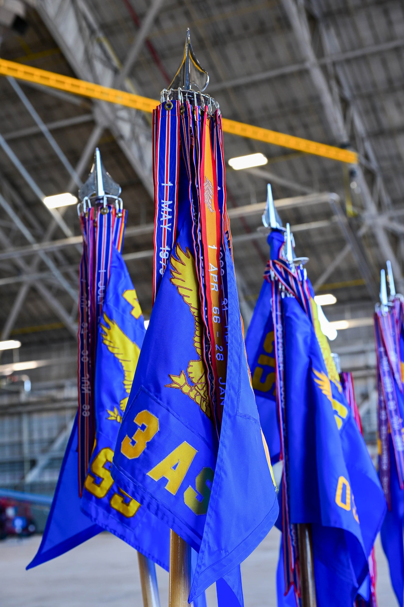 Guidons belonging to units at Dover Air Force Base stand in a hangar at the 2025 Honorary Commanders Induction Ceremony at Dover AFB, Delaware, Oct. 22, 2024. Forty-five local civic and business leaders were inducted into the HCC program during the ceremony. (U.S. Air Force photo by Mauricio Campino)