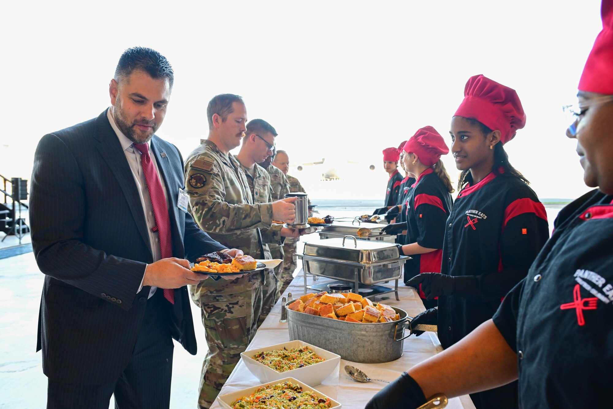 POLYTECH High School culinary art students serve a buffet-style lunch during the 2025 Honorary Commanders Induction Ceremony at Dover Air Force Base, Delaware, Oct. 22, 2024. Students enrolled in the program are introduced to concepts and methods of the restaurant industry. (U.S. Air Force photo by Mauricio Campino)