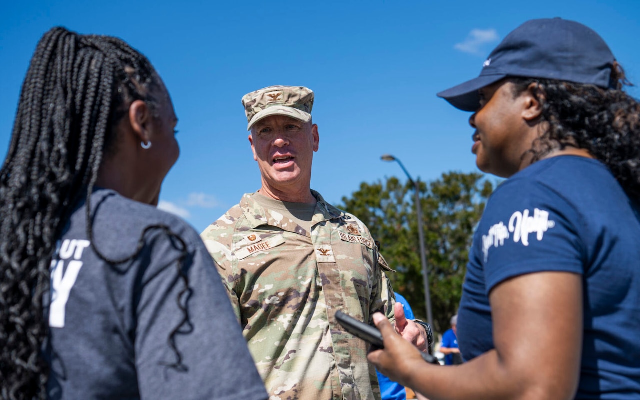 Two women chat with a soldier.