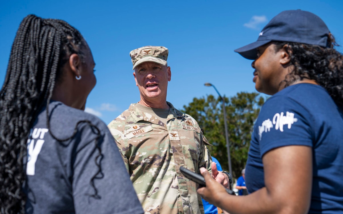 Two women chat with a soldier.