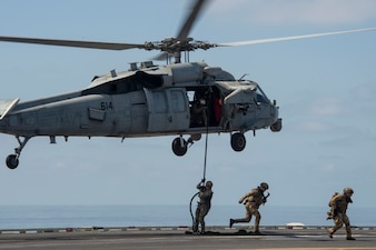 A U.S. Navy EOD technician and Italian marines rappel from an MH-60S Sea Hawk helicopter from HSC-14 during a fast-rope exercise aboard USS Abraham Lincoln (CVN 72).