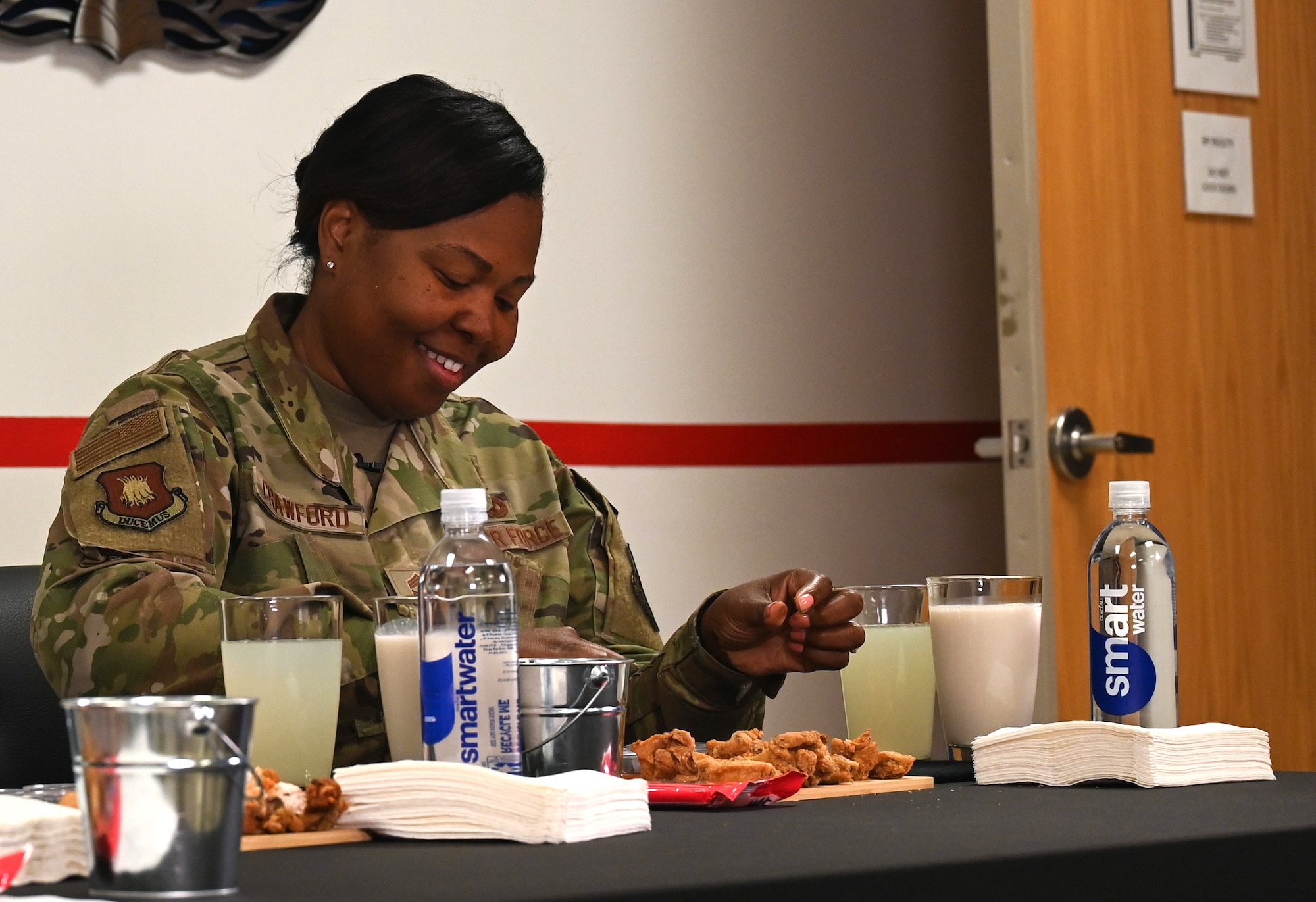 Chief Master Sgt. Markiesha Crawford, 22nd Air Refueling Wing command chief, dips a chicken wing in hot sauce during the 22nd Communications Squadron Cybersecurity Office Spicy Ones challenge Oct. 7, 2024, at McConnell Air Force Base, Kansas. Crawford, along with Col. Cory Damon, 22nd ARW commander, answered questions to raise awareness for Cybersecurity Awareness Month while eating increasingly spicy chicken wings. (U.S. Air Force photo by Staff Sgt. Tryphena Mayhugh)