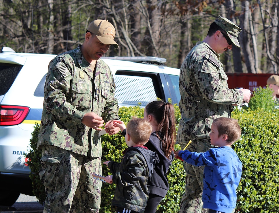 YORKTOWN, Va. (April 5, 2024) Ensign Darelle Moore, Naval Weapons Station (NWS) Yorktown’s Security Officer and Chief Ethan Holland, assigned to the installation’s Security Department, hand out stickers to military affiliated youths during a parade as part of the Month of the Military Child. (U.S. Navy Photo by Max Lonzanida/Released).