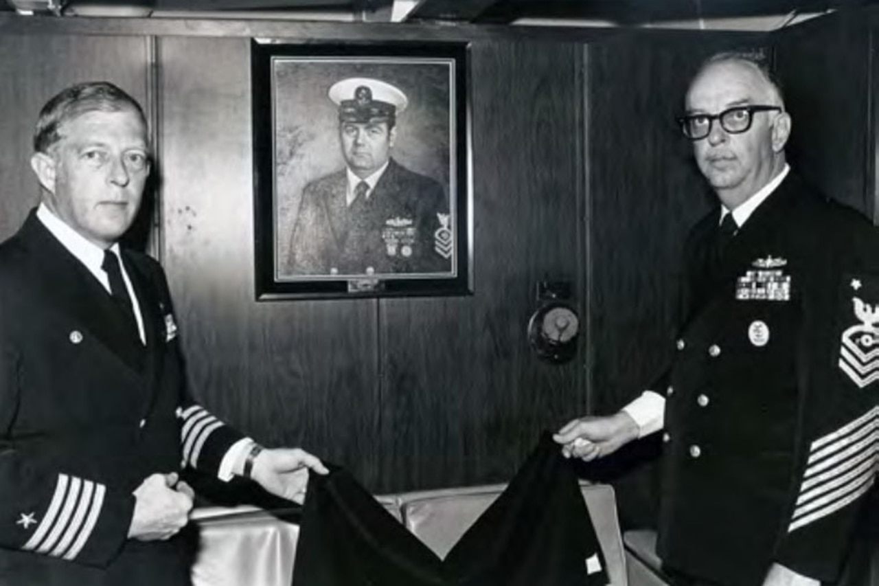 Sailors stand in front of an oil painting of a sailor.
