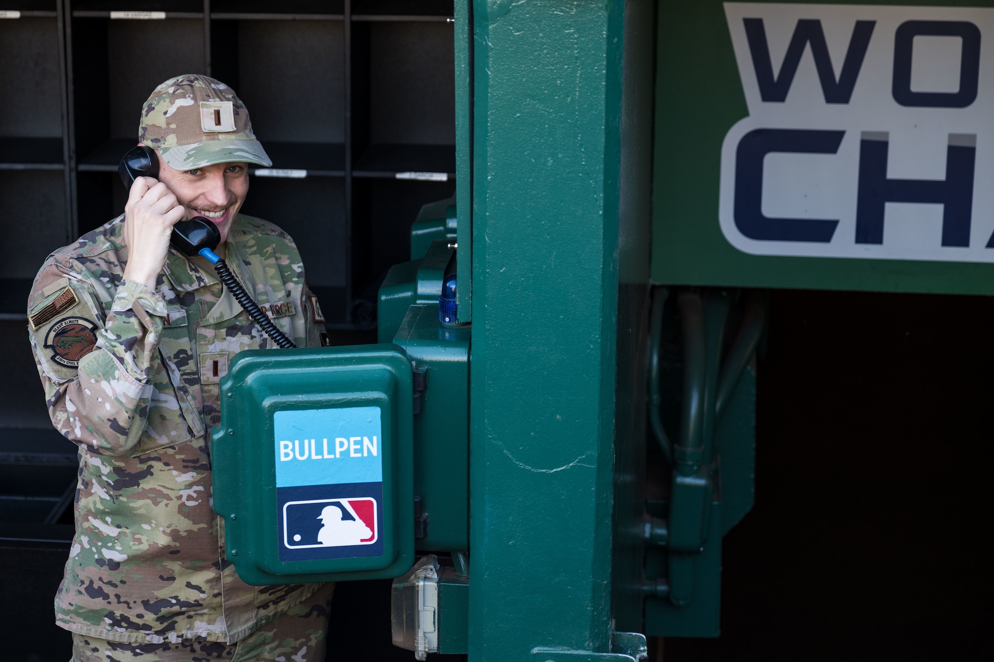 A U.S. Air Force 2nd Lieutenant pretends to make a phone call on the bullpen phone.