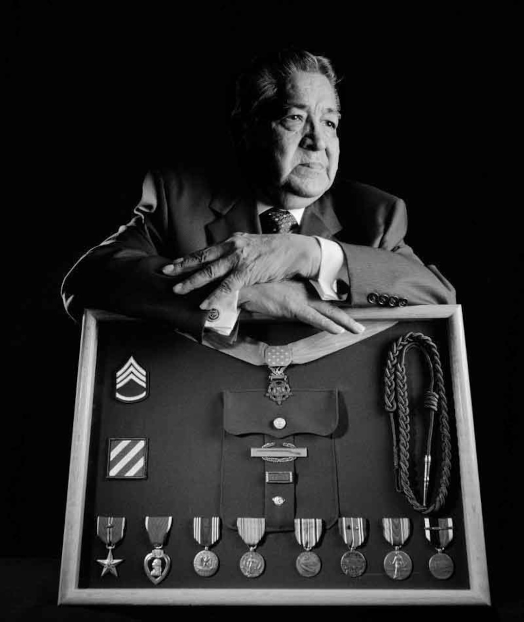 A man poses with several medals on a medal display board.