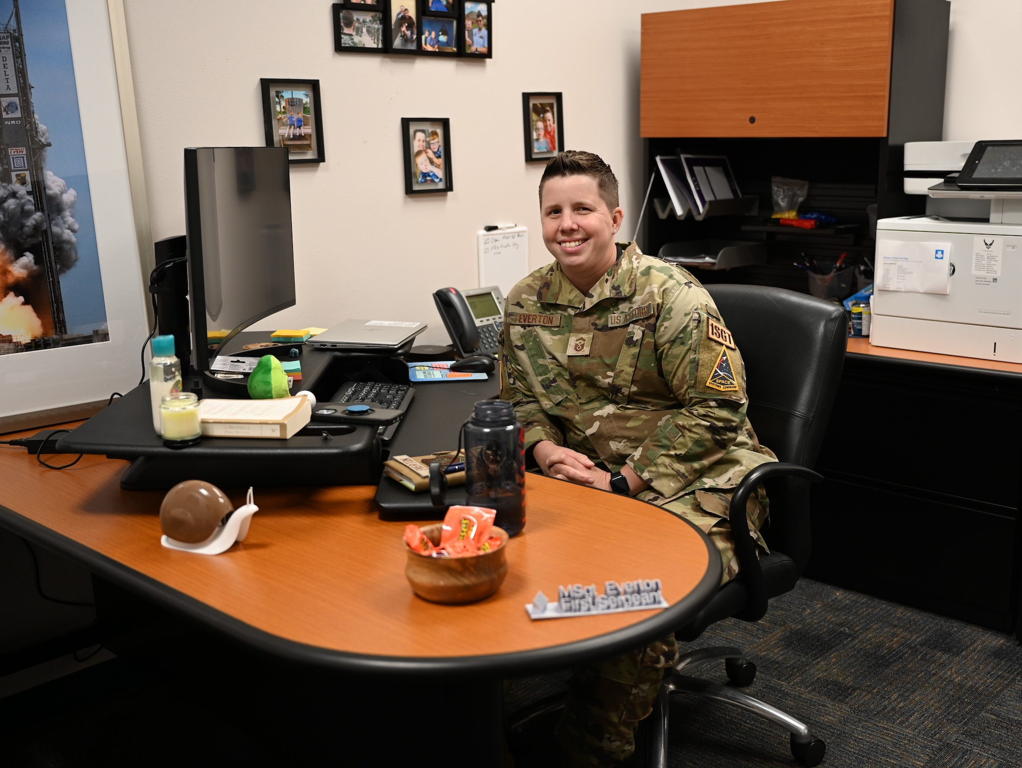 A woman, dressed in her military uniform, sits at her desk.