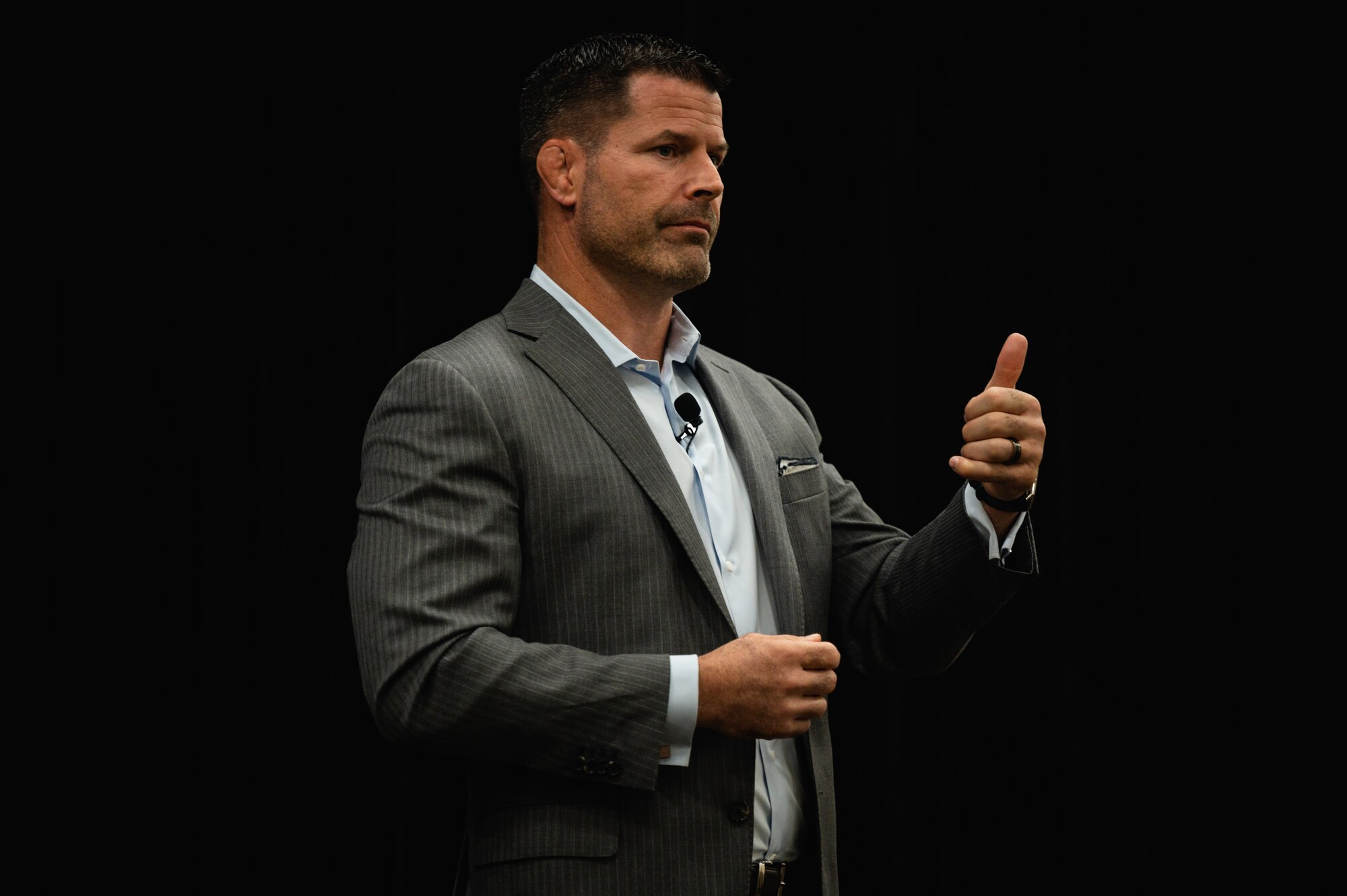 A man in a suit waives hands on stage