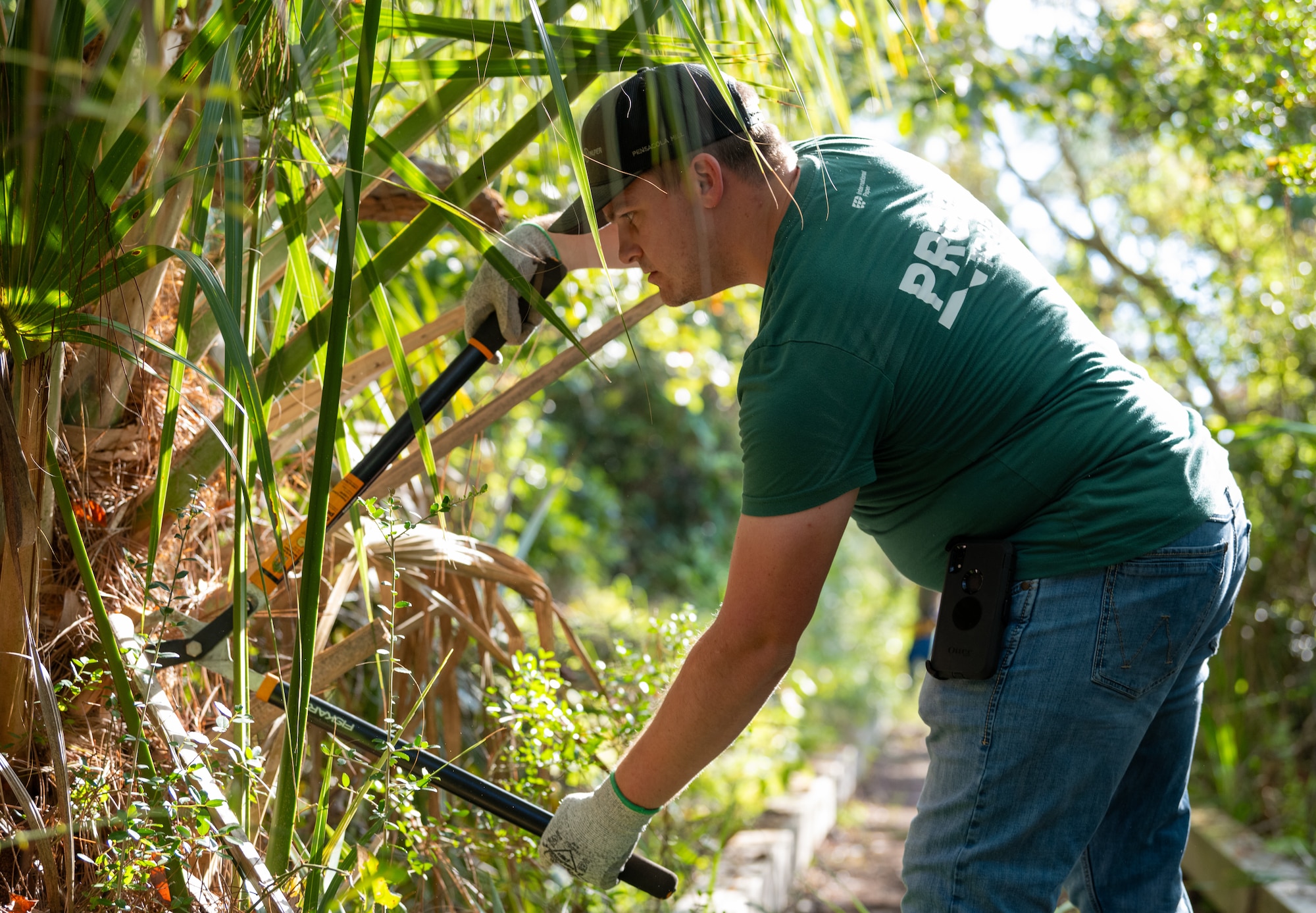 A volunteer from International Paper cuts excess leaves off a plant on Grace Brown Nature Trail at Hurlburt Field, Florida, Oct. 3, 2024.