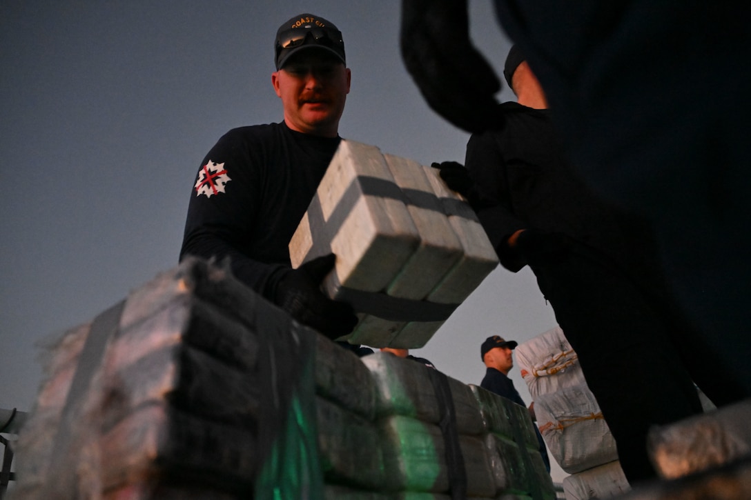 The crew of Coast Guard Cutter Resolute unload interdicted narcotics onto Sector St. Petersburg South Moorings, Florida, Oct. 23, 2024. Armed Coast Guardsmen stood watch over the interdicted drugs to ensure security and accountability of the seized contraband. (U.S. Coast Guard photo by Petty Officer 1st Class Riley Perkofski)