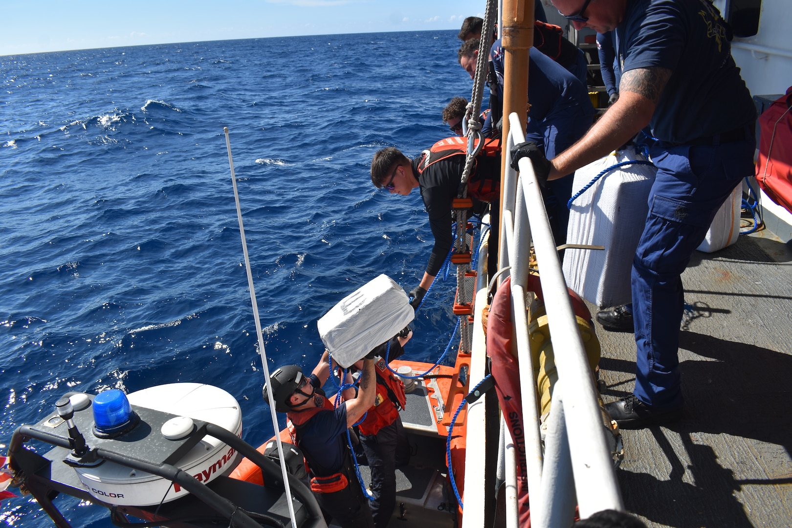 The crew of Coast Guard Cutter Resolute transfer interdicted narcotics at sea during a routine Caribbean patrol. (U.S. Coast Guard courtesy photo)