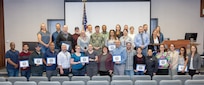 Capt. JD Crinklaw, commander, Puget Sound Naval Shipyard & Intermediate Maintenance Facility, poses for a portrait with Employee Resource Group award recipients, leaders, champions and supervisors, Oct. 8, 2024, following the annual PSNS & IMF ERG awards ceremony in the Shipyard Auditorium, in Bremerton, Washington. (U.S. Navy photo by Wendy Hallmark)