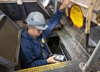 Michael Galvez, shipfitter worklead, Navy competent person, Shop 11, Shipfitters Gas Free, works inside the roller pit of a large flange turning machine, Oct. 18, 2024, while completing a gas-free inspection in Building 460 at Puget Sound Naval Shipyard & Intermediate Maintenance Facility in Bremerton, Washington. (U.S. Navy photo by Wendy Hallmark)