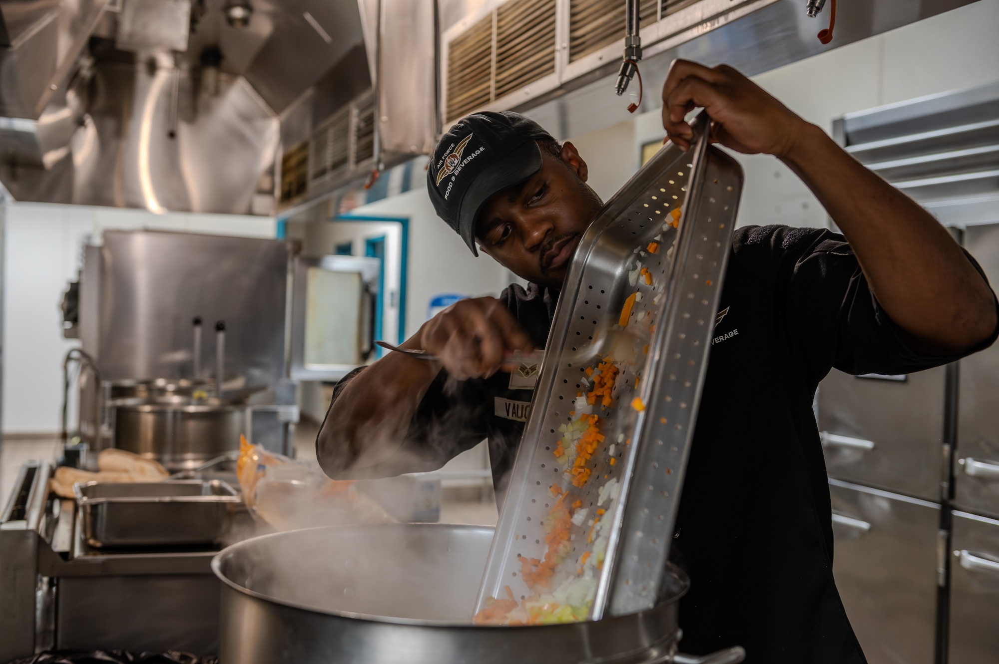 U.S. Air Force Senior Airman Richard Vaughn III, 1st Special Operations Force Support Squadron food service shift leader, pours a tray of freshly cut carrots and onions into a large pot in the kitchen of the Riptide Dining Facility on Hurlburt Field, Florida, Oct. 1, 2024.