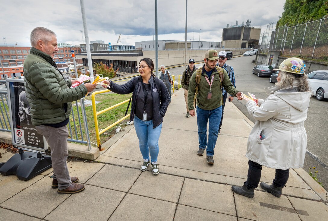 Command safety advocates hand out safety gear to employees as they exit State Street Gate Oct. 17, 2024, during the annual fall and winter “Can You See Me Now” safety campaign at Puget Sound Naval Shipyard & Intermediate Maintenance Facility in Bremerton, Washington. (U.S. Navy photo by Wendy Hallmark)