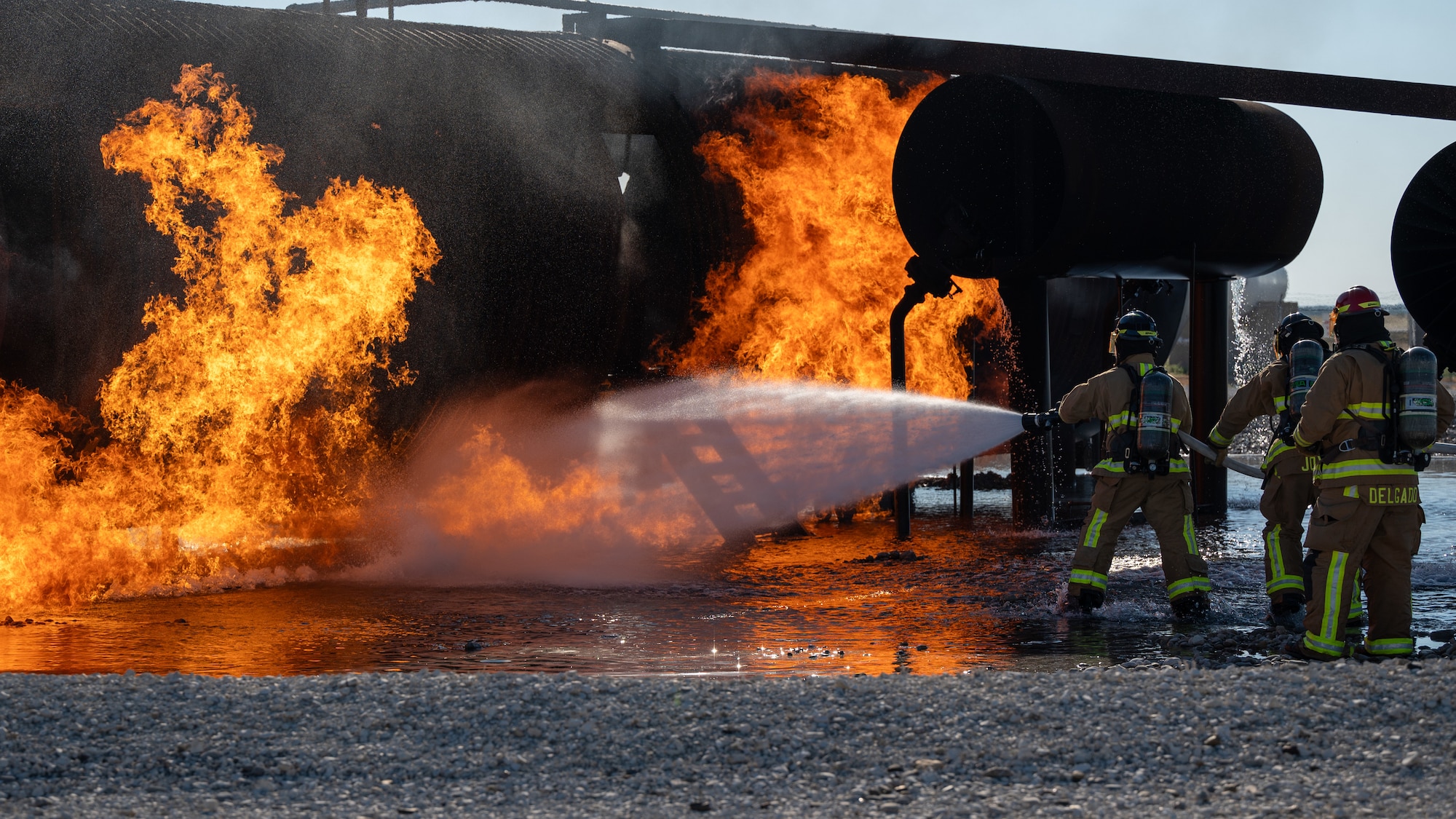 Firefighters from the 47th Civil Engineer Squadron spray water at the base of the fuselage of an aircraft live fire simulator at Laughlin Air Force Base, Texas, Oct. 15, 2024. Firefighters at Laughlin continually train, both in the classroom and at live fire simulators. (U.S. Air Force photo by Staff Sgt. Nicholas Larsen)