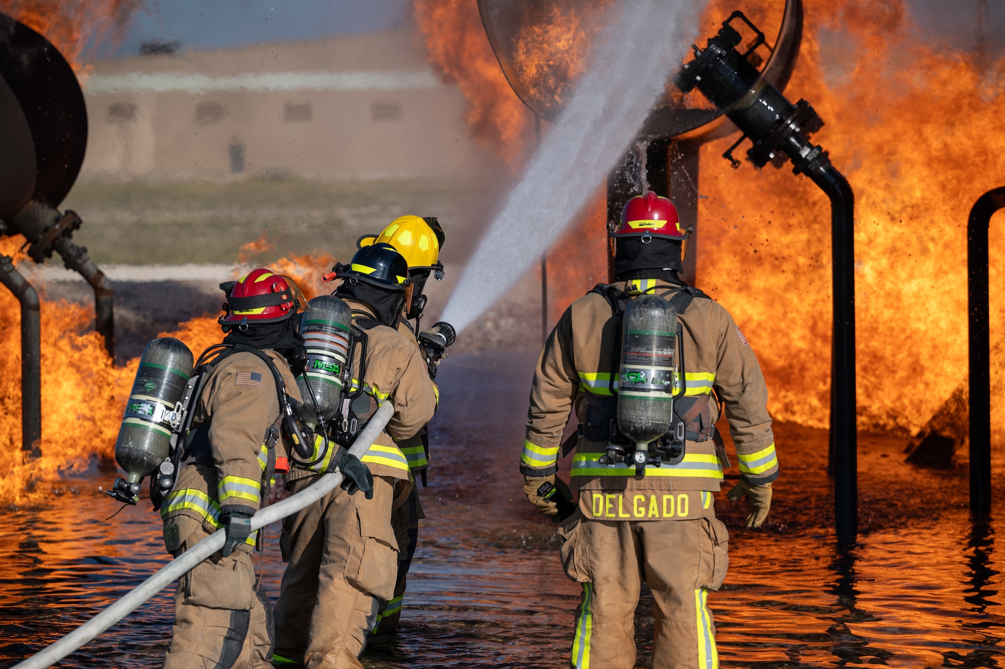 Firefighters from the 47th Civil Engineer Squadron spray water at a simulated engine cell on an aircraft live fire simulator at Laughlin Air Force Base, Texas, Oct. 15, 2024. When fighting fires in an engine cell firefighters will move the stream of water in a circular motion to hit all areas of the fire. (U.S. Air Force photo by Staff Sgt. Nicholas Larsen)