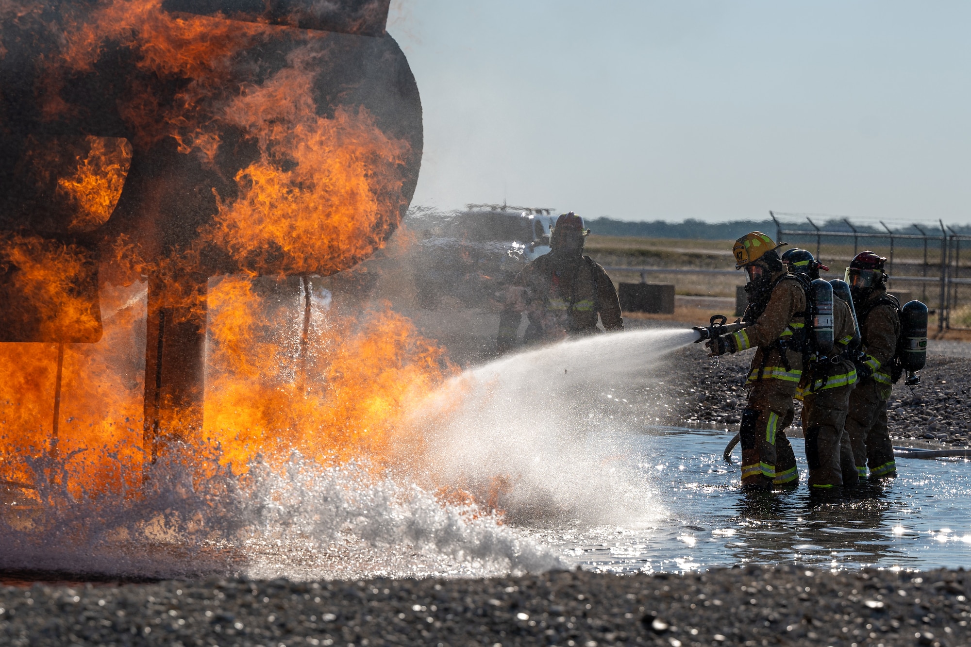 Firefighters from the 47th Civil Engineer Squadron spray water at a groundfire at an aircraft live fire simulator at Laughlin Air Force Base, Texas, Oct. 15, 2024. The simulator at Laughlin uses propane as the fuel for the fires that firefighters will put out. (U.S. Air Force photo by Staff Sgt. Nicholas Larsen)