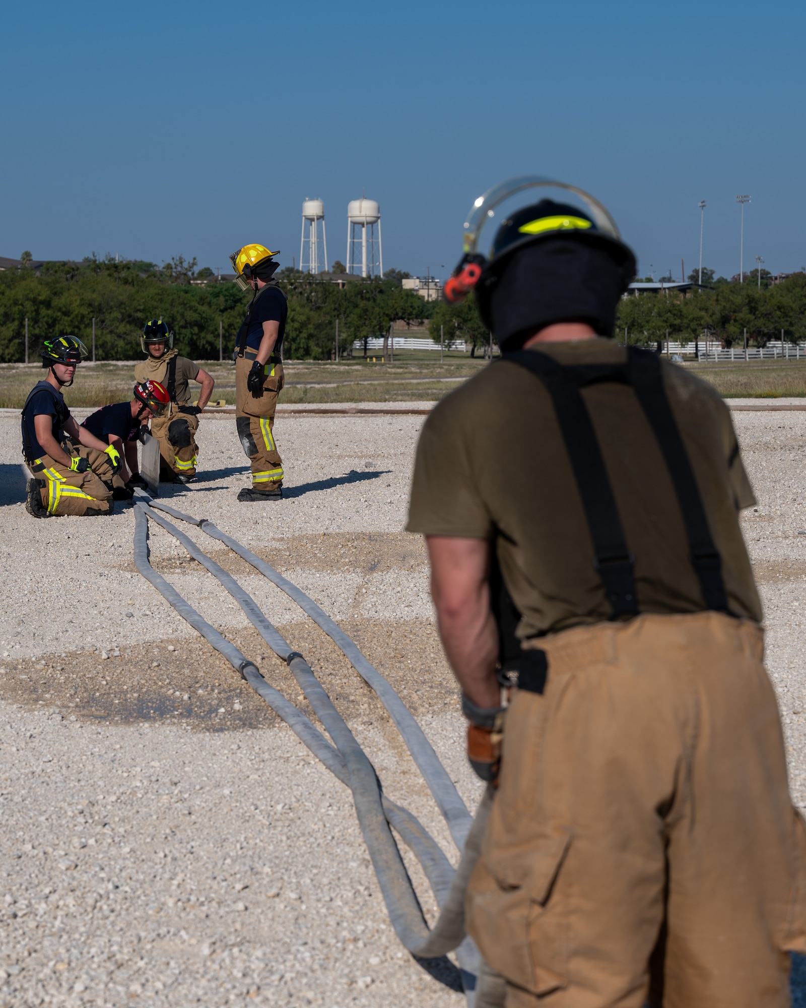 Firefighters from the 47th Civil Engineer Squadron roll up hoses after training at Laughlin Air Force Base, Texas, Oct. 15, 2024. Hoses need to be drained and rolled after use for storage, preparing them for the next time they need to be used. (U.S. Air Force photo by Staff Sgt. Nicholas Larsen)