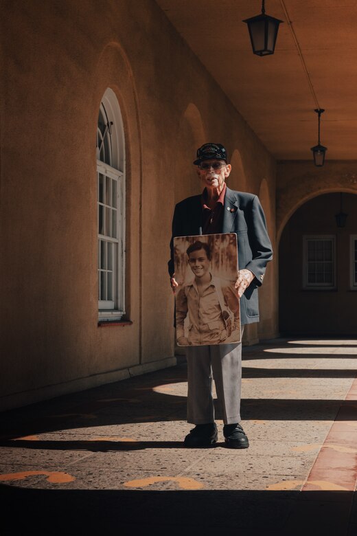 Retired U.S. Marine Corps Maj. Billy Hall, a veteran of World War II, the Korean War, and Vietnam War, poses with a photo of his younger self when he was serving in WWII at Guadalcanal while standing on the Yellow Footprints at Marine Corps Recruit Depot San Diego, California, Oct. 11, 2024. Hall visited MCRD San Diego to attend a graduation ceremony for Bravo Company, 1st Recruit Training Battalion. The Yellow Footprints are iconic to the Depot as all recruits stand upon them to receive initial instruction during their immediate arrival for training to become Marines. (U.S. Marine Corps photo by Cpl. Alexander O. Devereux)
