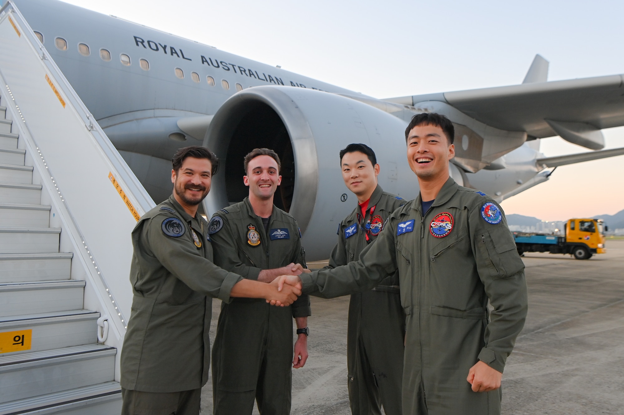 Royal Australian Air Force KC-30A pilots shake hands with Republic of Korea Air Force KC-330 pilots in front of a RAAF KC-30A tanker aircraft with a blue sky in the background.
