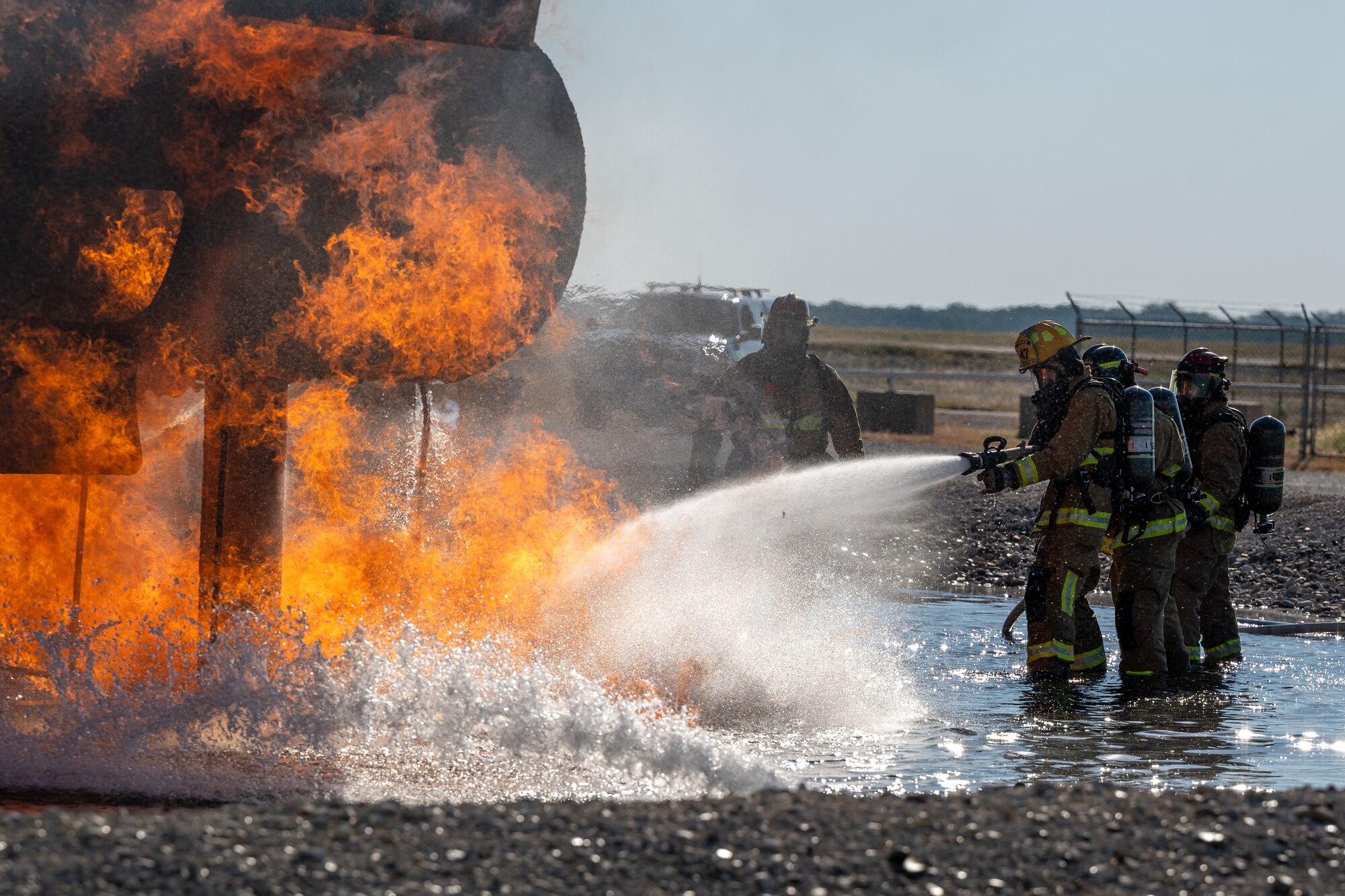 Firefighters from the 47th Civil Engineer Squadron spray water at a groundfire at an aircraft live fire simulator at Laughlin Air Force Base, Texas, Oct. 15, 2024. The simulator at Laughlin uses propane as the fuel for the fires that firefighters will put out. (U.S. Air Force photo by Staff Sgt. Nicholas Larsen)