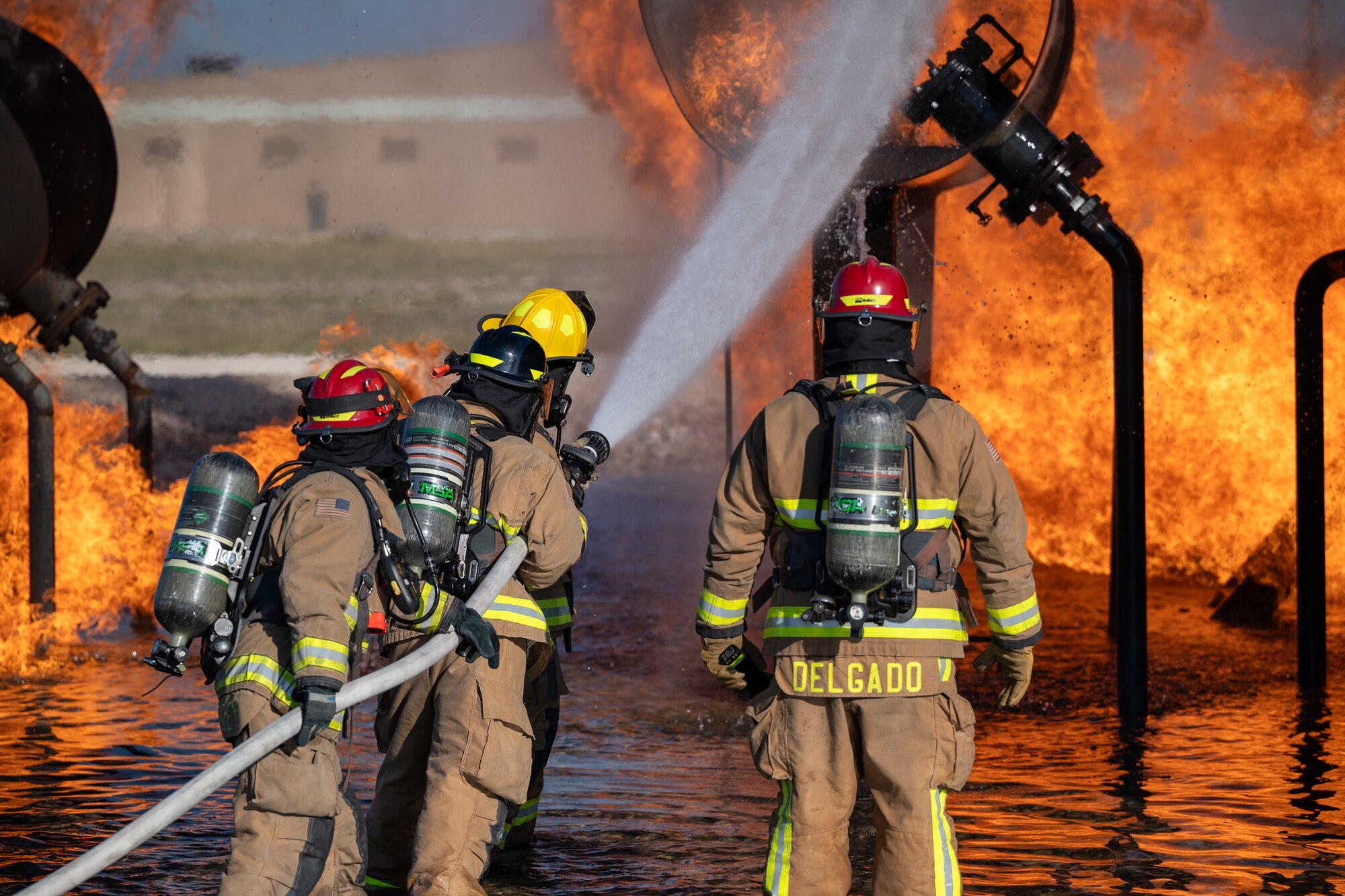 Firefighters from the 47th Civil Engineer Squadron spray water at a simulated engine cell on an aircraft live fire simulator at Laughlin Air Force Base, Texas, Oct. 15, 2024. When fighting fires in an engine cell firefighters will move the stream of water in a circular motion to hit all areas of the fire. (U.S. Air Force photo by Staff Sgt. Nicholas Larsen)