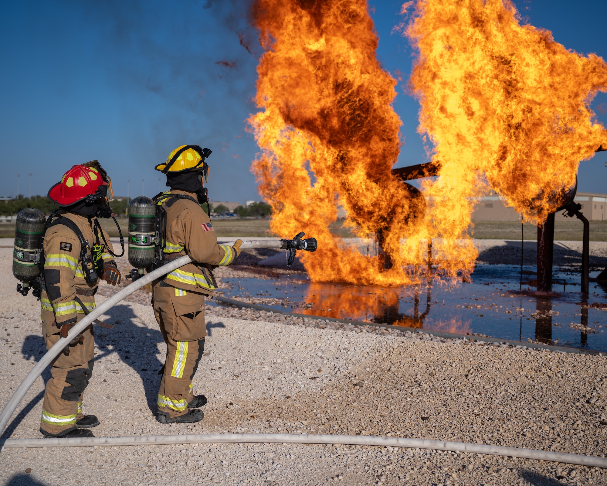 Firefighters from the 47th Civil Engineer Squadron prepare to fight a live fire simulator at Laughlin Air Force Base, Texas, Oct. 15, 2024. Live fire simulations are valuable training opportunities for Airmen, who get to put classroom training into practice while dealing with the stress and heat of flames. (U.S. Air Force photo by Staff Sgt. Nicholas Larsen)