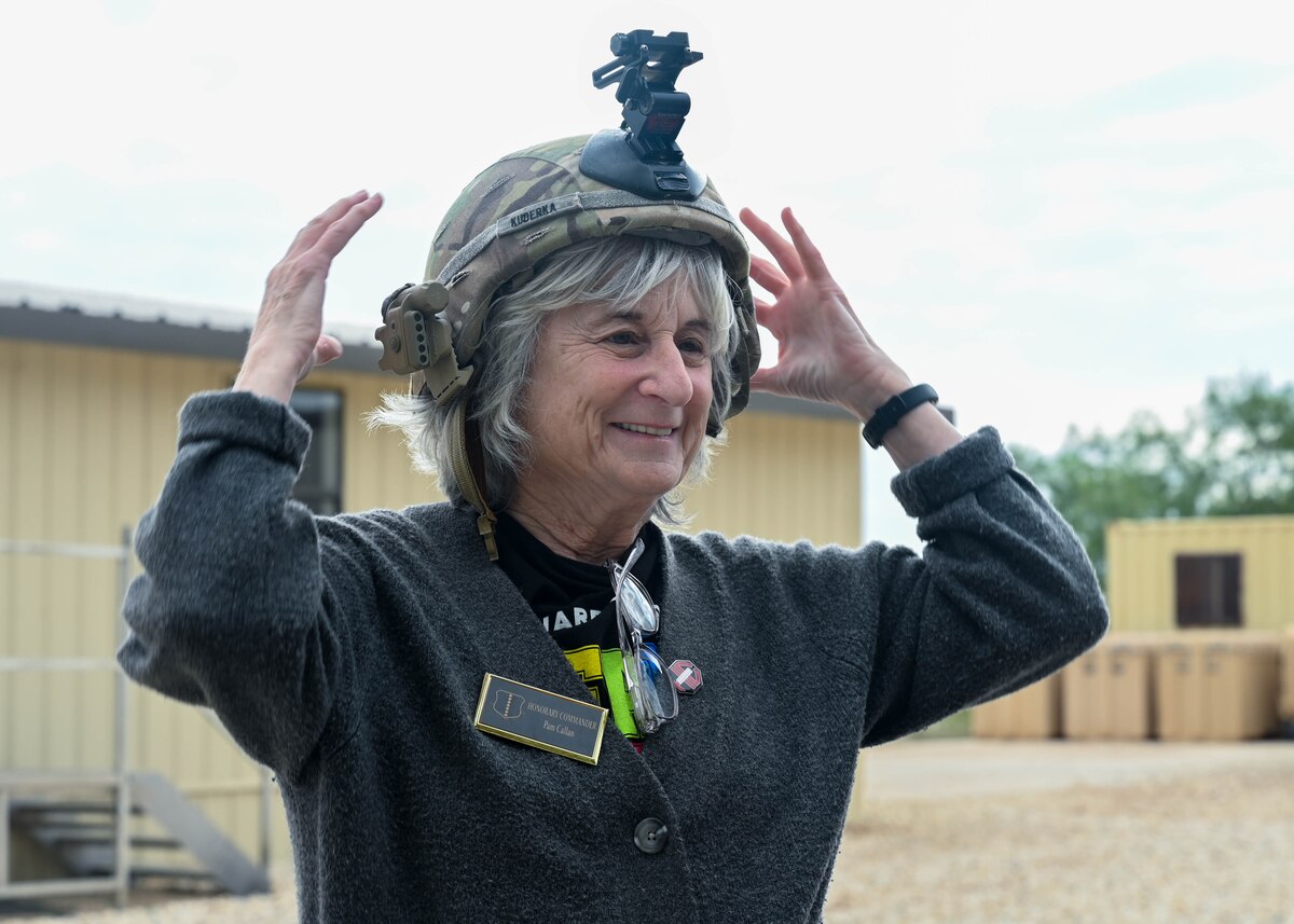 Pam Callan, 17th Training Wing Honorary Commander, wears a protective helmet while visiting Command Post Sentinel, Goodfellow Air Force Base, Texas, Oct. 18, 2024. U.S. Army Lt. Col. Raymond Kuderka, 344th Military Intelligence Battalion Commander, brought out gear for the honorary commanders to wear and examine. (U.S. Air Force photo by Senior Airman Zach Heimbuch)
