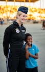 woman in uniform poses for a photo next to child