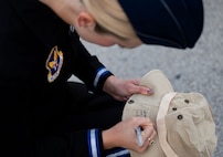 woman in uniform signs "Madison Marsh, Miss America 2024" on a hat