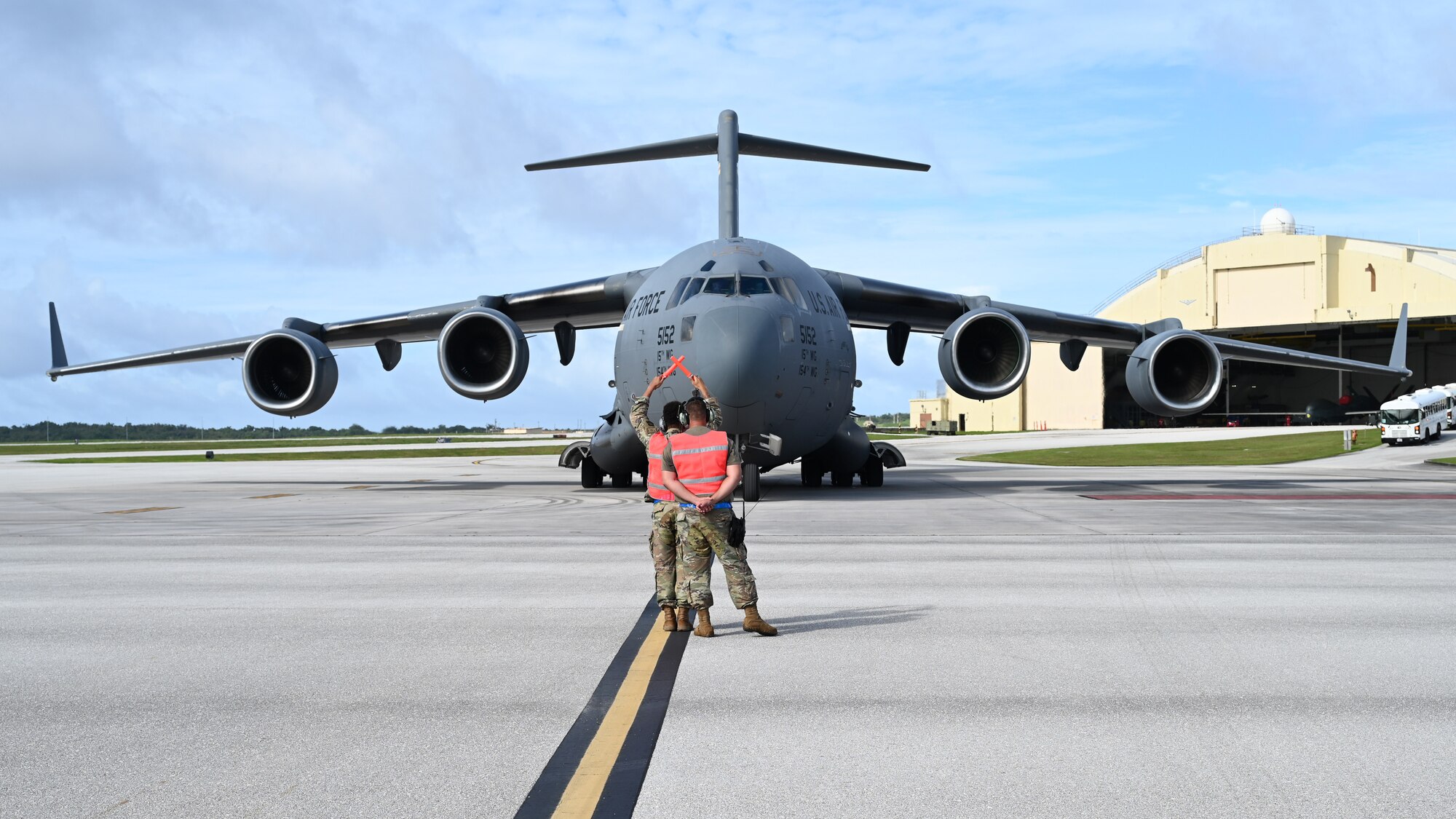 An Airman guides another Airman on how to marshal a C-17 Globemaster on the flightline.