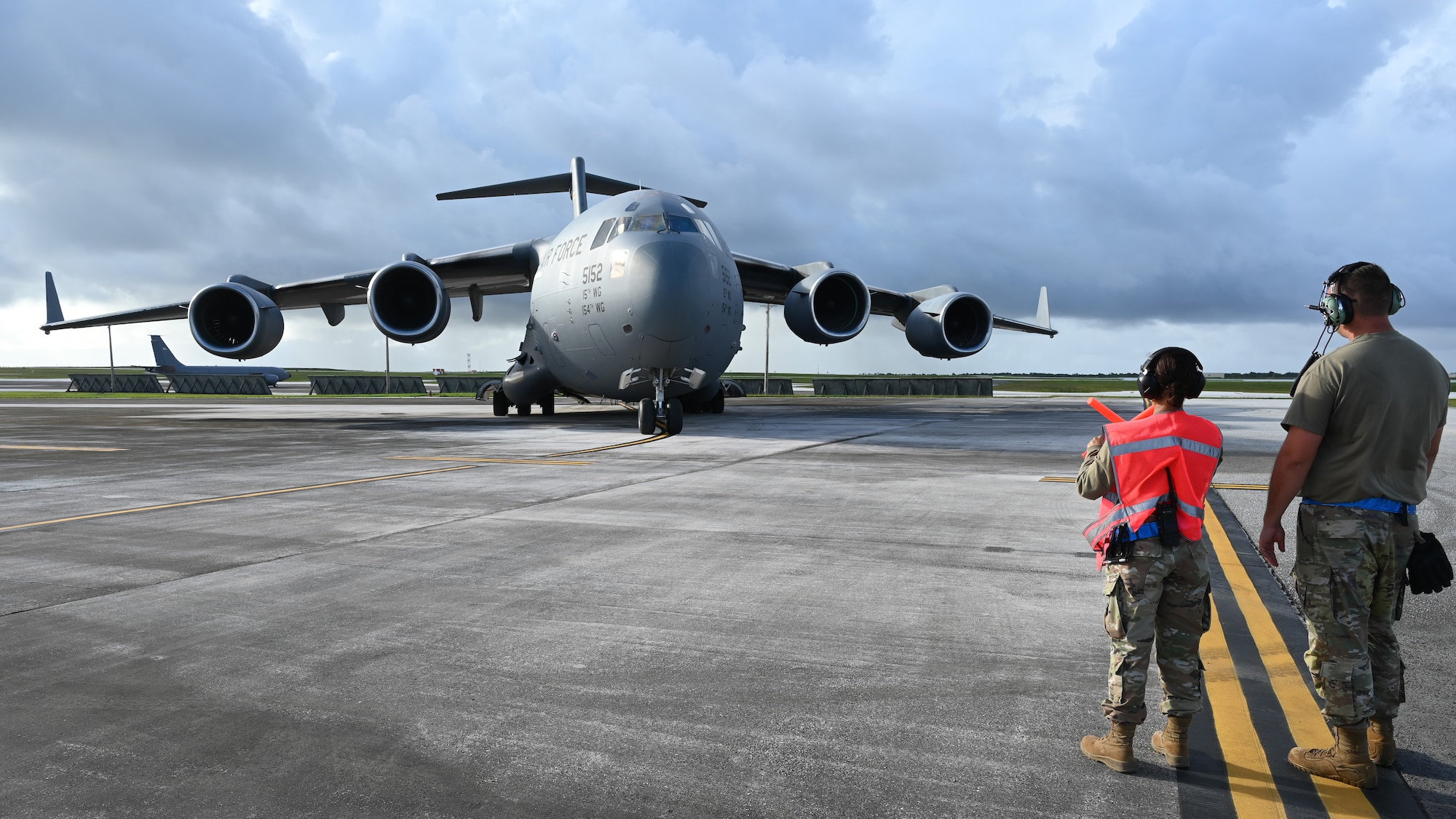 An Airman coaches another Airman on how to marshal a C-17 Globemaster on the flightline.