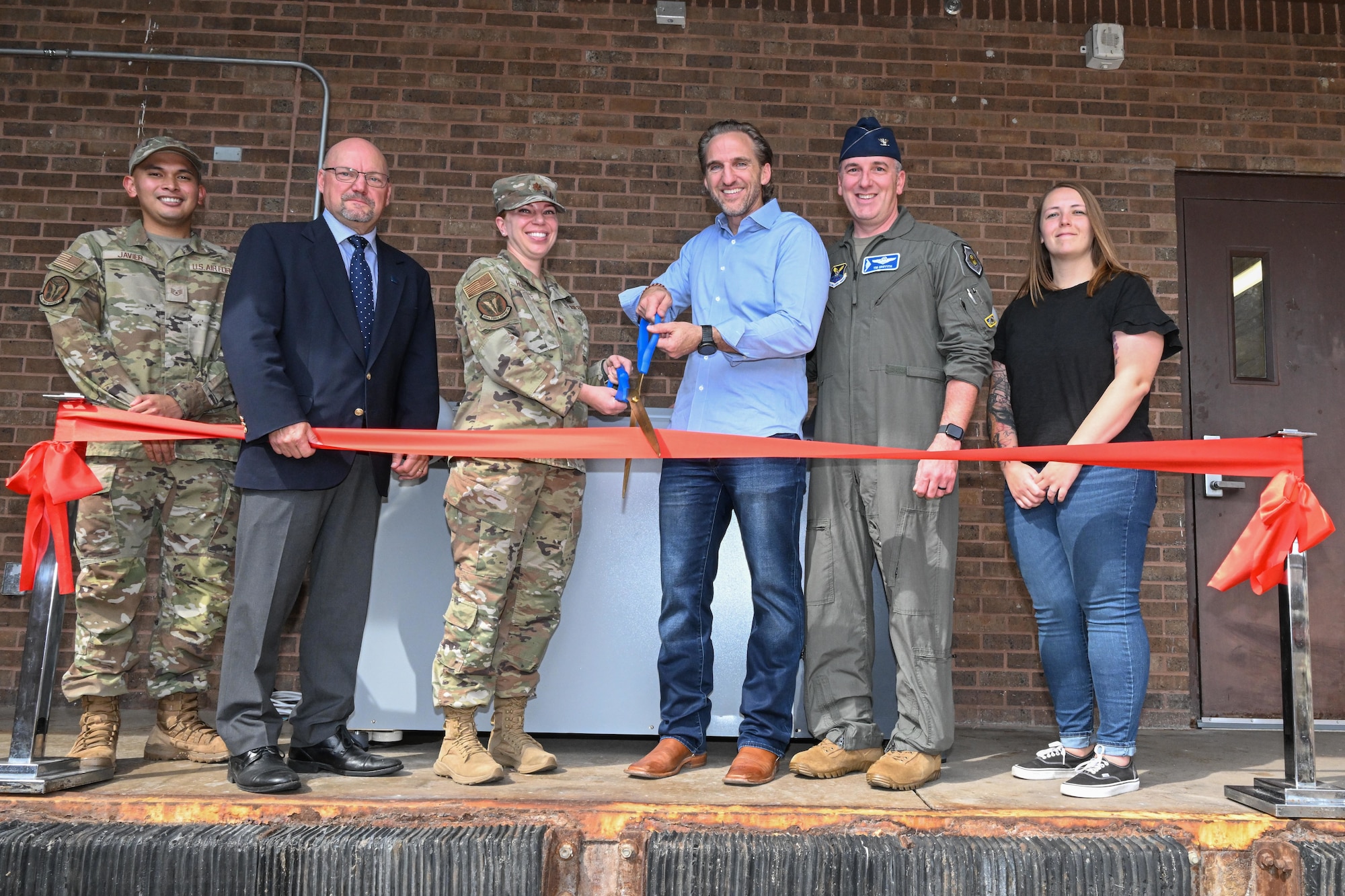 Members from the 509th Force Support Squadron cut a ceremonial ribbon during the unveiling of the dining facility's new composter on Whiteman Air Force Base, Mo. on Sept. 18, 2024. The new composter is the first of its kind in the Department of Defense, able to fully compost the food waste, unlike a traditional dehydrator, which performs one phase of the process, and it is also the first of its size in the United States. (U.S. Air Force photo by Phil Stuart)
