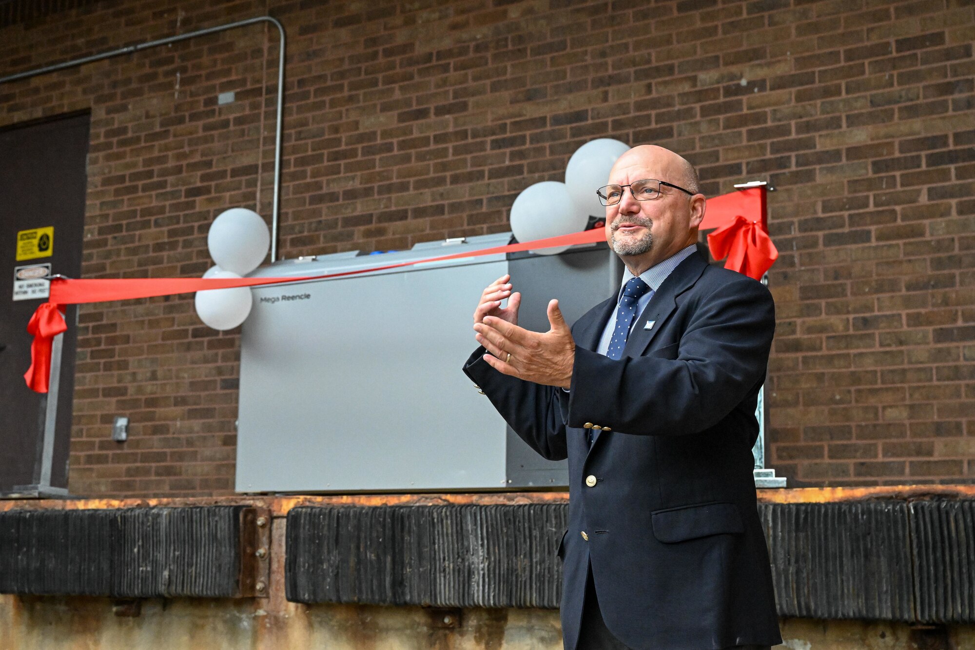 Members from the 509th Force Support Squadron cut a ceremonial ribbon during the unveiling of the dining facility's new composter on Whiteman Air Force Base, Mo. on Sept. 18, 2024. The new composter is the first of its kind in the Department of Defense, able to fully compost the food waste, unlike a traditional dehydrator, which performs one phase of the process, and it is also the first of its size in the United States. (U.S. Air Force photo by Phil Stuart)