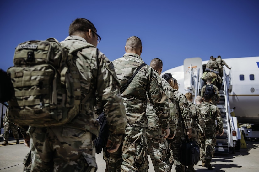 Soldiers line up to board a plane.