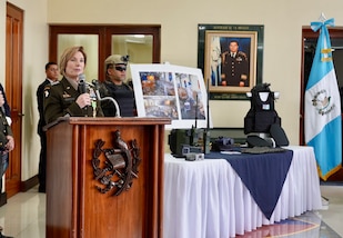 A female uniformed military officer speaks from a podium.