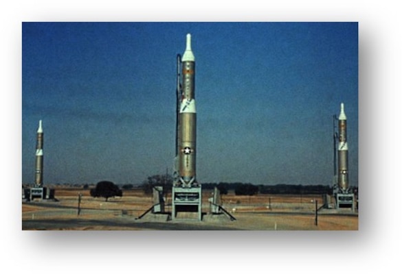 Three Titan I missiles are shown atop their launch bays.