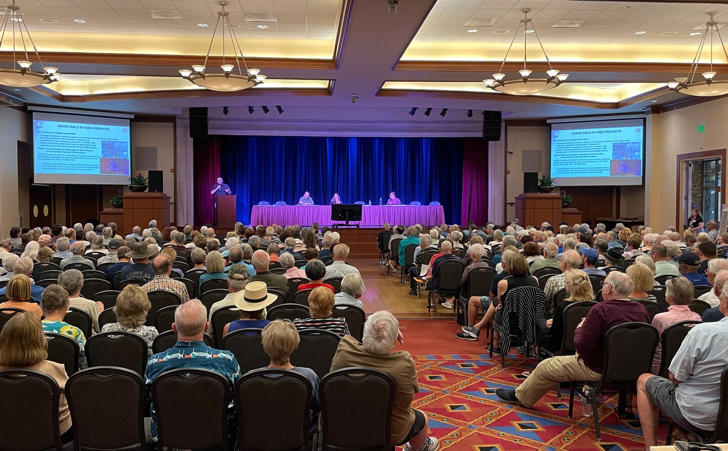 A ballroom with hundreds of seated spectators as U.S. Army Corps of Engineers representatives present from a stage.