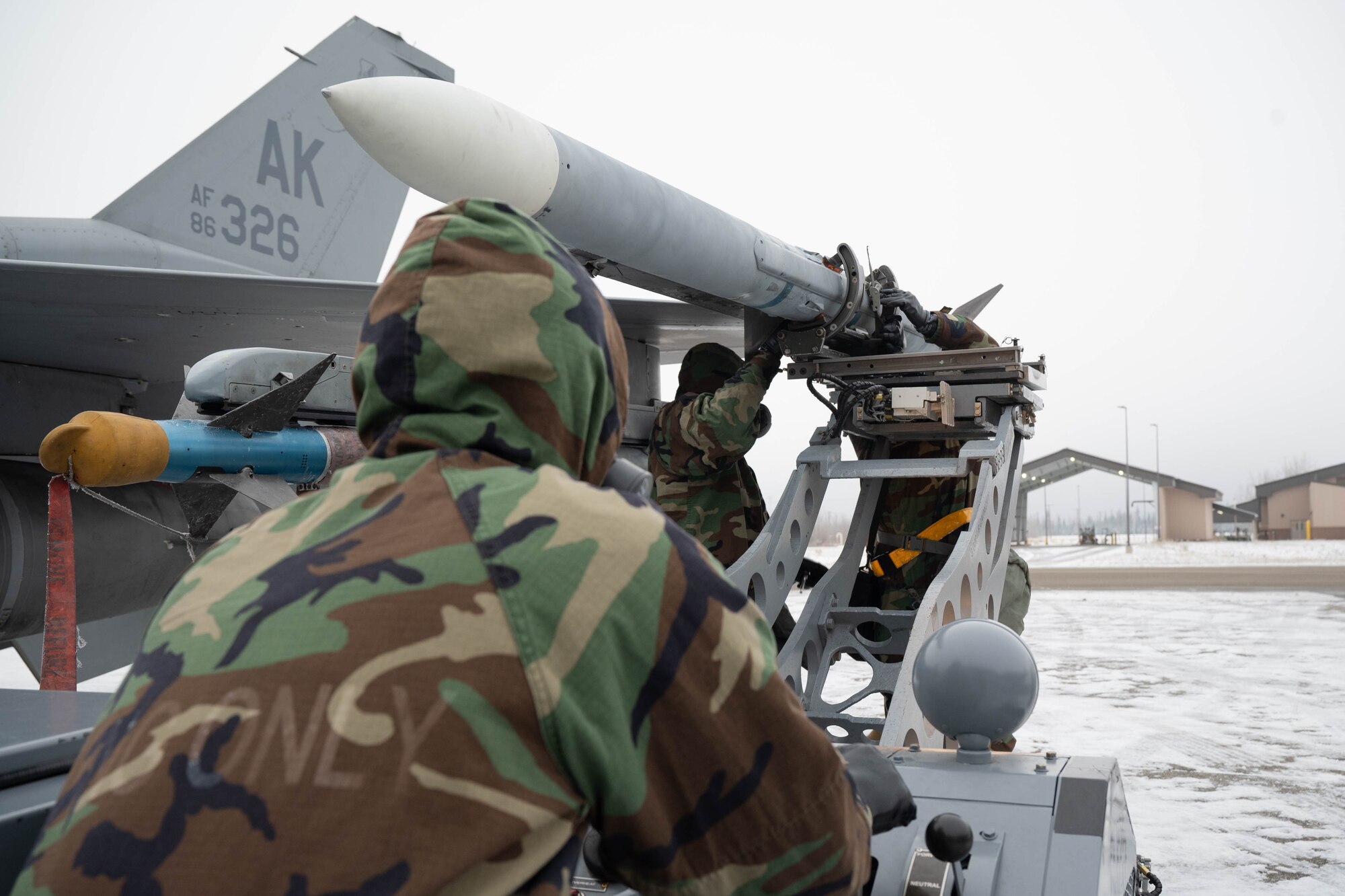 U.S. Airmen from the 18th Fighter Generation Squadron load an AIM-120 Advanced Medium-Range Air-to-Air Missile onto an F-16 Fighting Falcon aircraft during the third quarter load competition at Eielson Air Force Base, Alaska, Oct. 18, 2024.