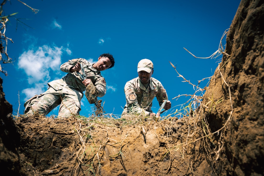 Two Airmen dig a hole.