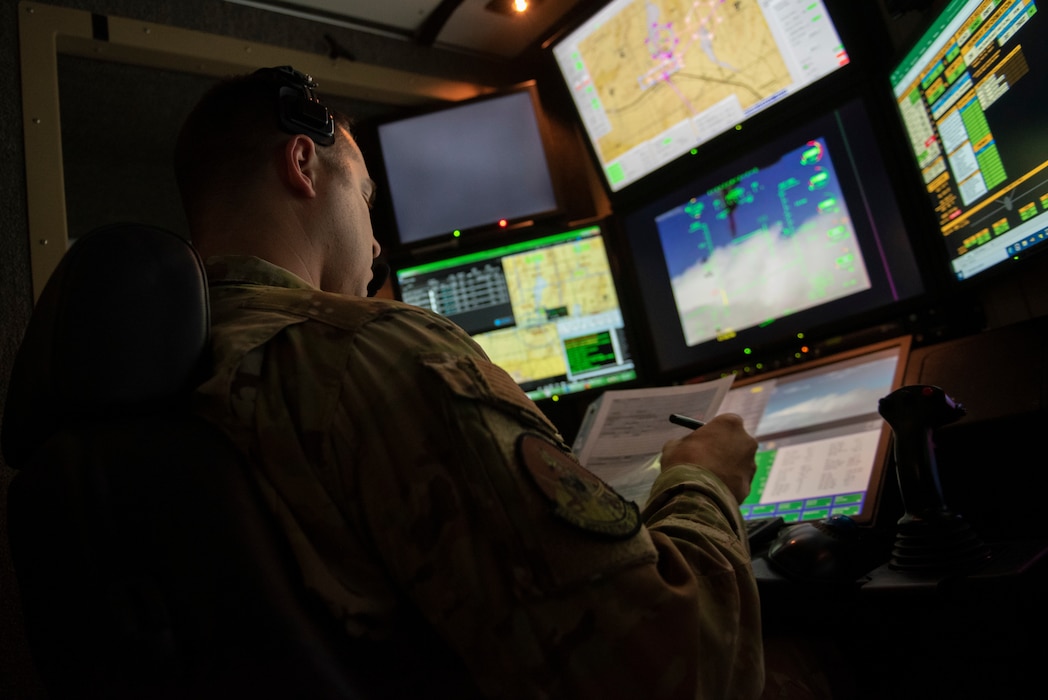 A man in a military uniform operates a remotely piloted aircraft flight simulator.