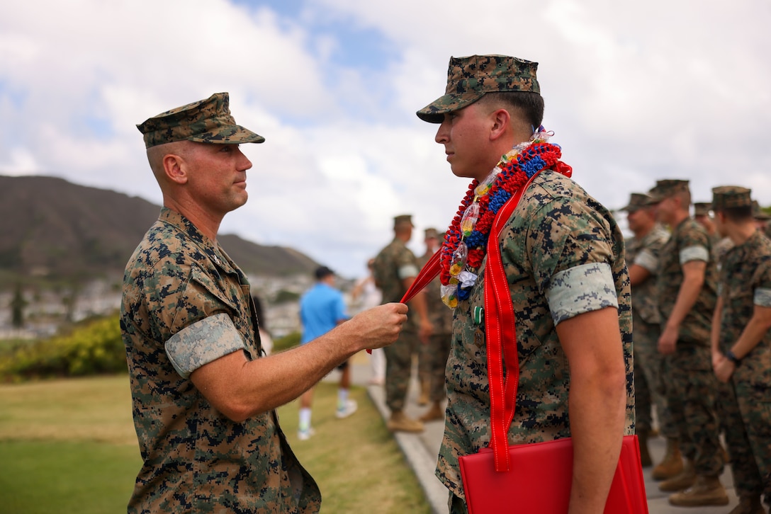 U.S. Marine Corps Col. Mark Schaefer, left, commanding officer, congratulates Cpl. Sean Olson, administrative specialist, both with Headquarters and Service Battalion, U.S. Marine Corps Forces, Pacific, after his meritorious promotion and award ceremony on Marine Corps Base Hawaii, Sept. 13, 2024. Olson, a California native, received a Navy and Marine Corps Commendation Medal for rescuing two people who were struggling to stay afloat in rough waters. He also earned a meritorious promotion, ahead of normal service requirements, signifying his outstanding performance as a Marine. (U.S. Marine Corps photo by Lance Cpl. Chloe Zimmerer)