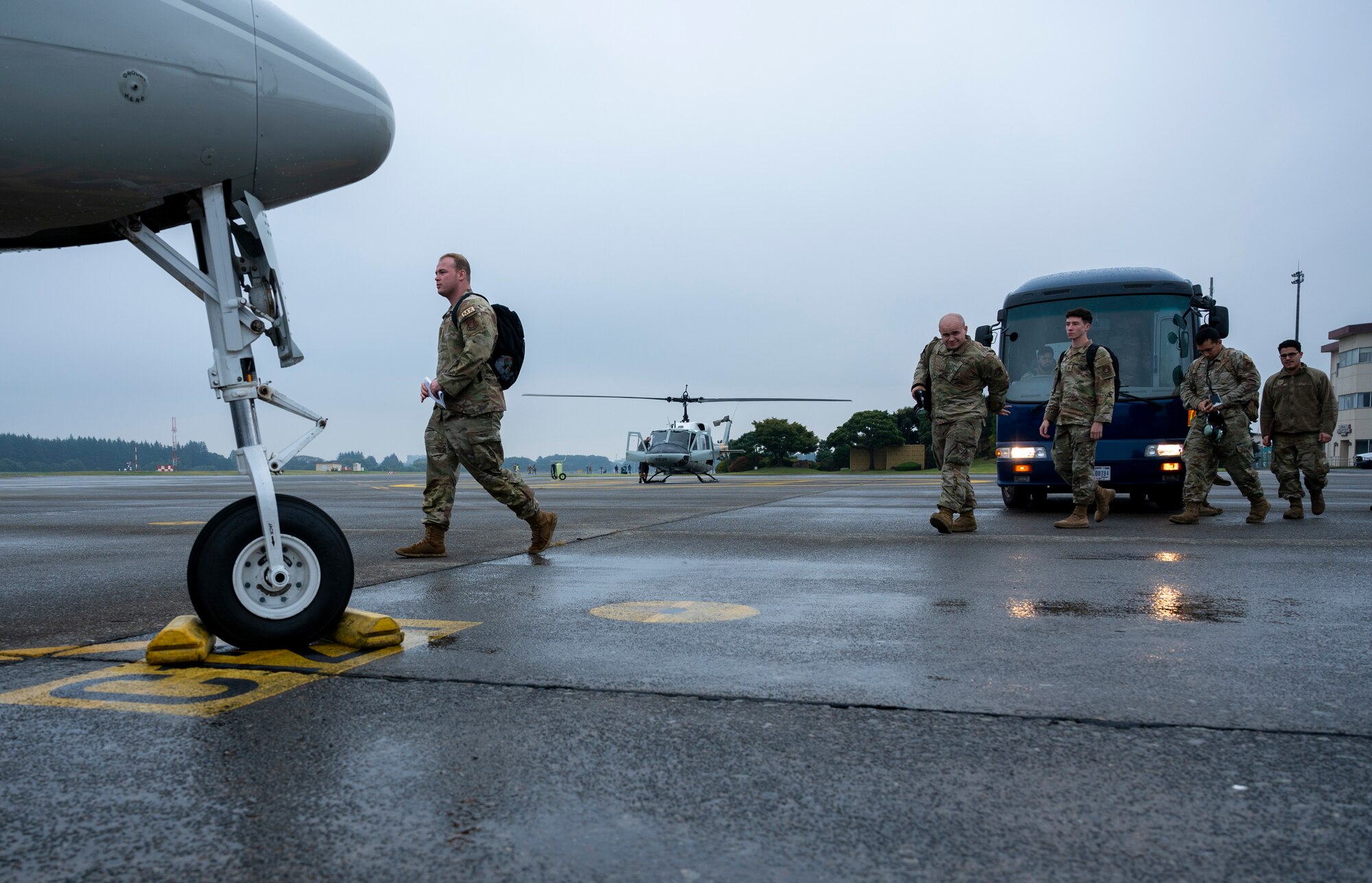 Military members walk off a bus a head towards a C-12J aircraft.